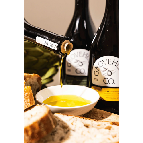Grovehood Collective Spanish & Italian extra virgin olive oil bottle at a table with bread