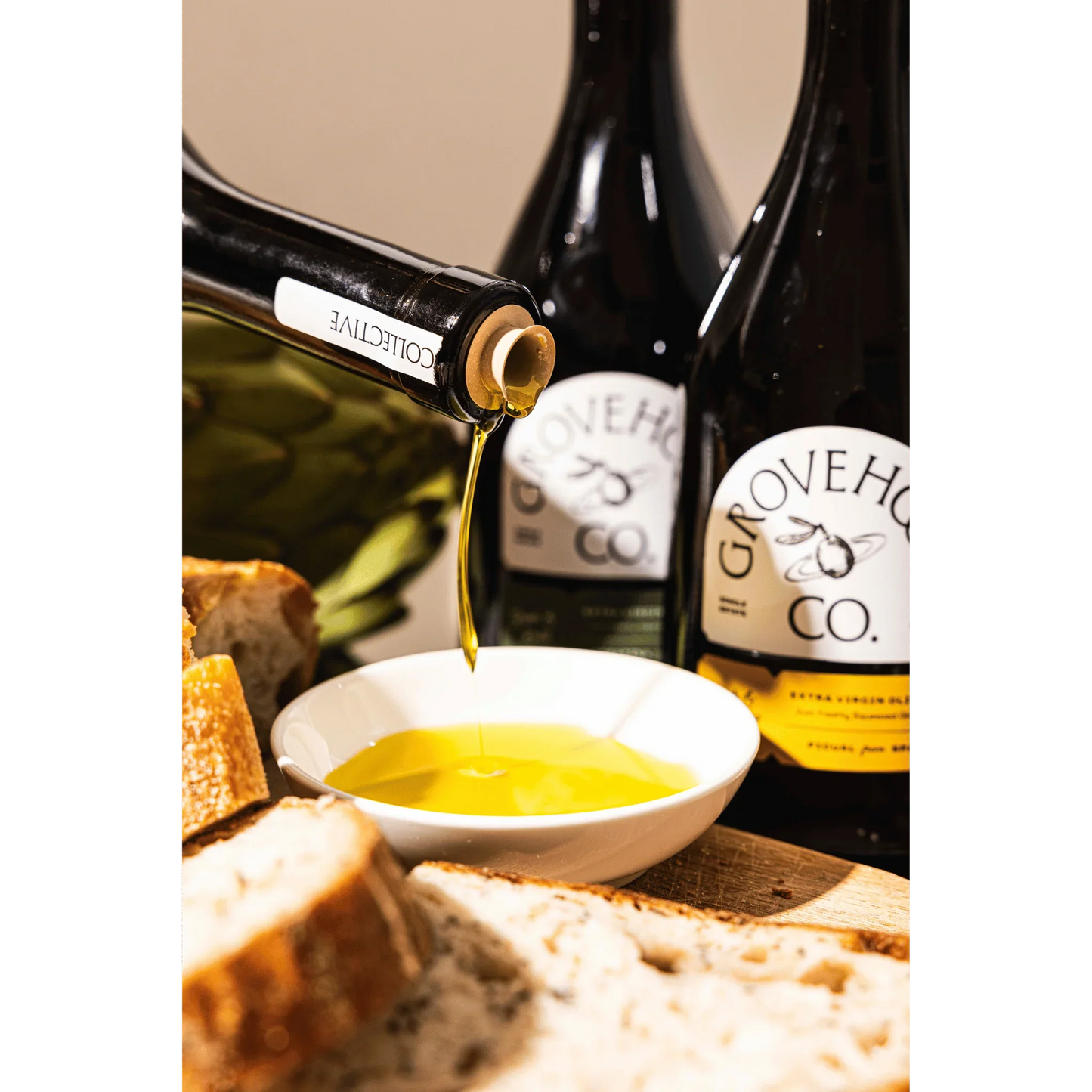 Grovehood Collective Spanish & Italian extra virgin olive oil bottle at a table with bread