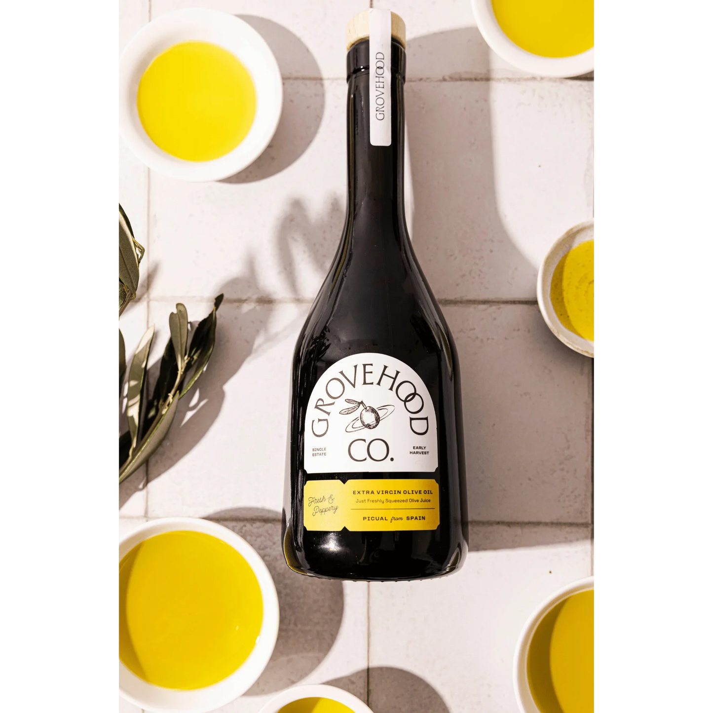 Grovehood Collective Spanish extra virgin olive oil bottle laid flat on a tile