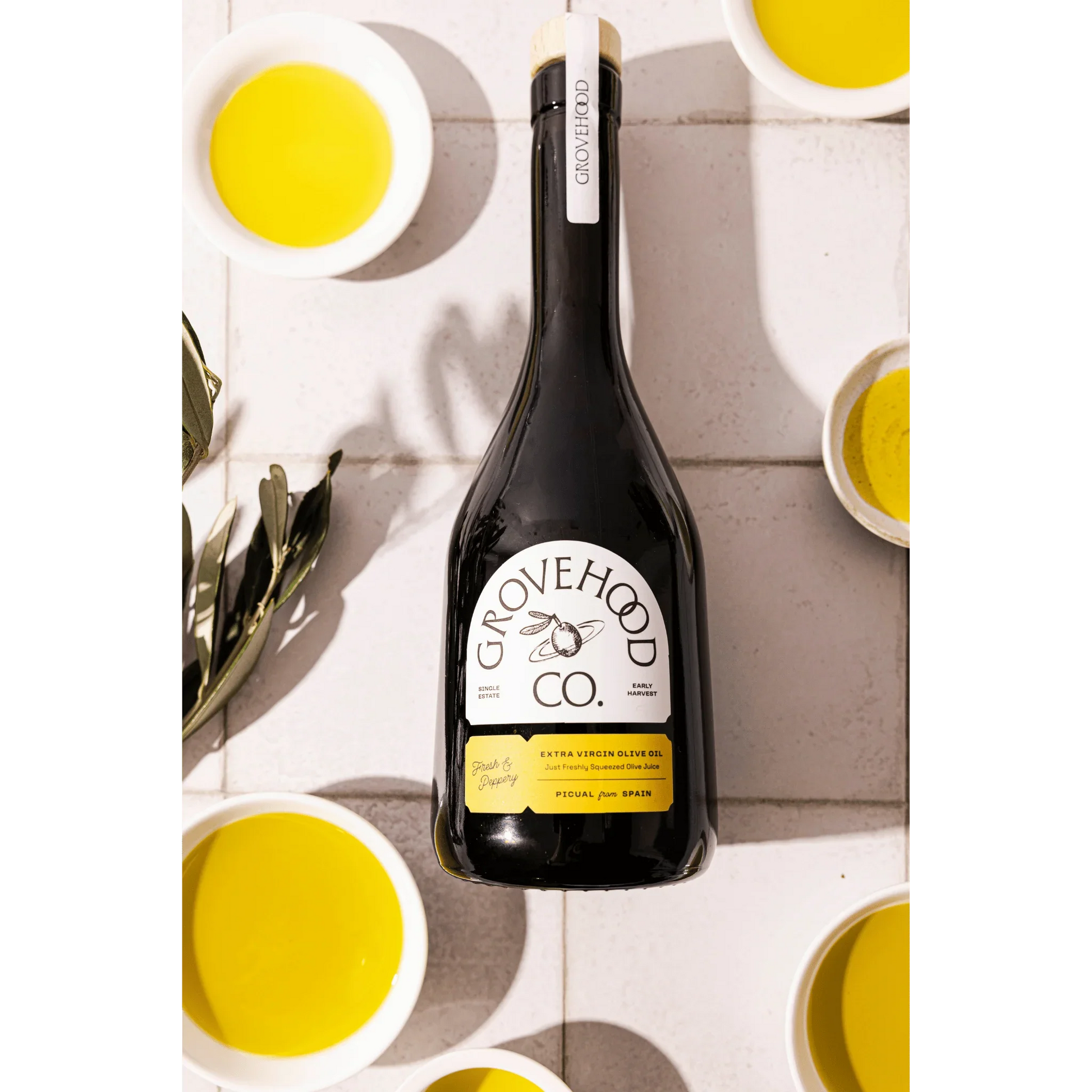 Grovehood Collective Spanish extra virgin olive oil bottle laid flat on a tile
